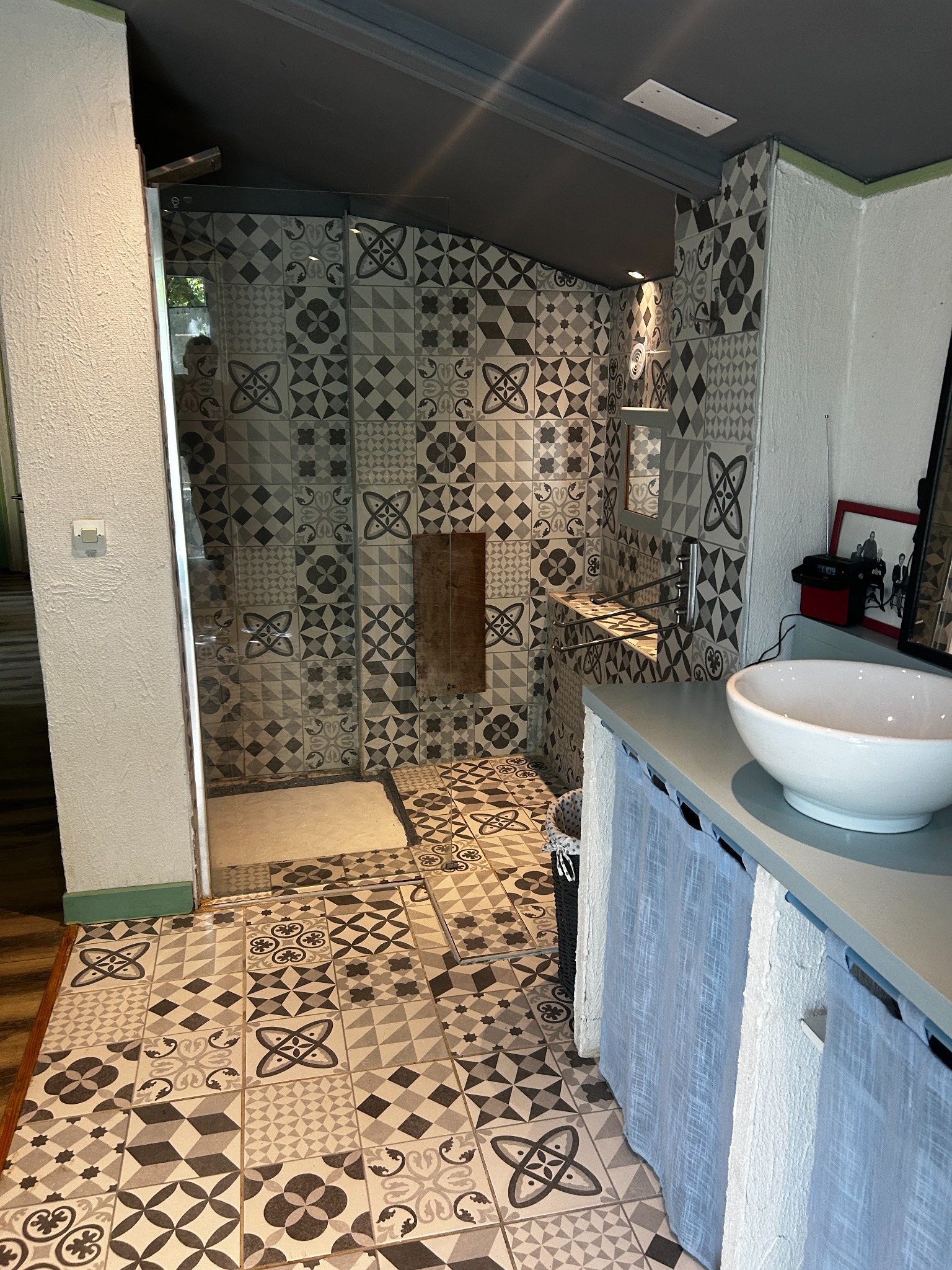 La douche de la salle de bain et son carrelage à motifs